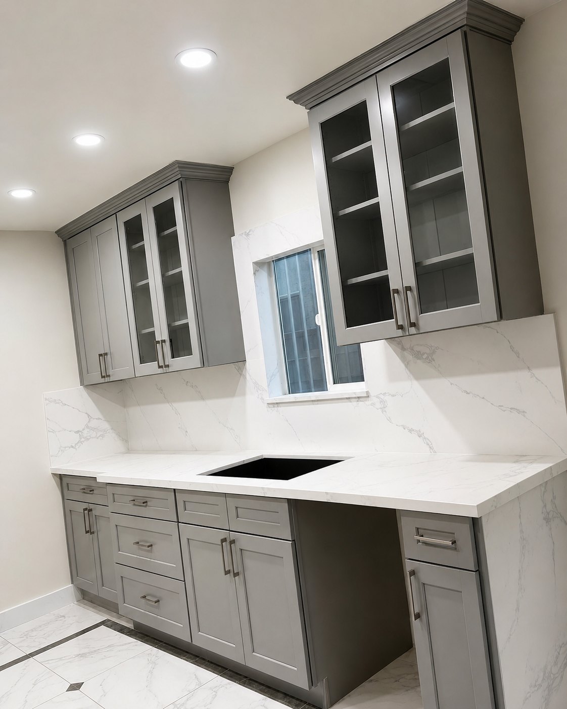 Gray Shaker cabinets with glass doors and quartz backsplash